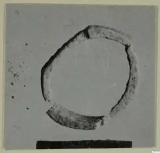 Faience ring, broken into several fragments, photographed against a plain grey background