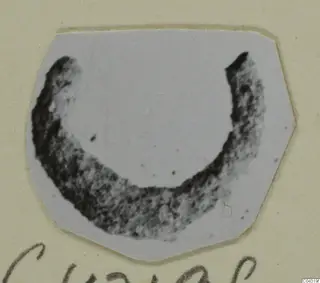 Dark crescent-shaped loop, open at the top, a jewellery find from Amathus tomb 2-26 photographed on a card