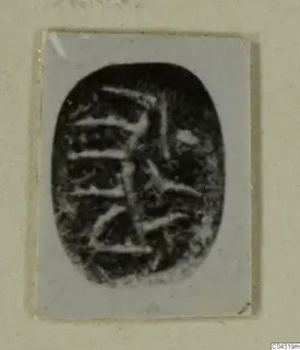 Oval seal-stone with an engraved linear pattern, photographed on a pale card.
