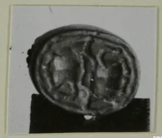 Glyptic from Amathus: an oval engraved object with a ridged rim, photographed on a dark block.