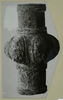 Single upright grooved object with a bulbous middle, shown in a photograph mounted on a card