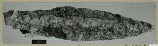Corroded iron weapon blade from Amathus, long and narrow, tapering to a point at the right end.