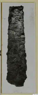 Corroded iron tool from Amathus, long and narrow, shown alone on a mounted print