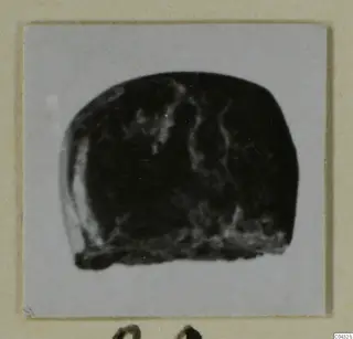 Dark stone object from Amathus, photographed on a pale grey card mount