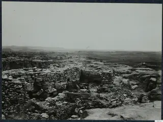 Idalion acropolis, stone walls and scattered rubble during excavation, with a open plain and hills beyond