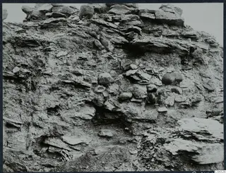 Vertical excavated section at Idalion Acropolis, with layers of flat stone slabs and rounded stones set in soil