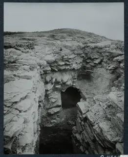 Excavation on the Acropolis at Idalion: a cut through layered pale rock leading to a dark opening