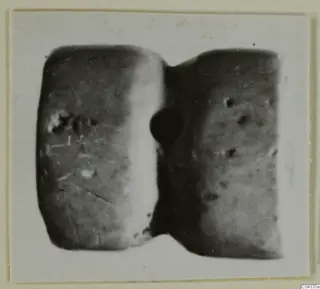Glyptic object from Ayia Irini: a small piece with two rounded faces joined by a narrow waist, photographed close up