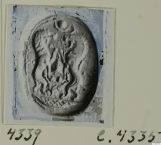 Oval seal or gem with carved wavy lines and a crosshatched band along the lower edge, shown in a photograph mounted on card.