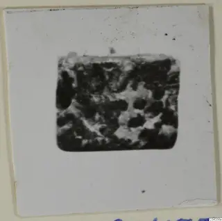Blurred photograph of a stone object, mounted on a white card.