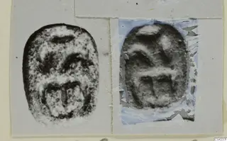 Two oval seal objects shown as prints side by side on a grey card mount, one with a torn blue-tinted backing