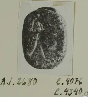 Oval dark stone seal or gem with faint pale engraved lines, shown on a mounted card