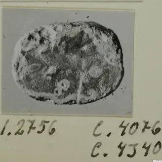 Oval seal or gem with a pitted, worn surface and faint engraved motifs.