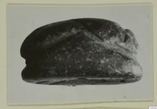Glyptic find from Ayia Irini: a dark stone seal or gem with a domed back and a raised ridge across it.