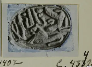 Oval seal or gem with a carved design, shown on a photograph mount