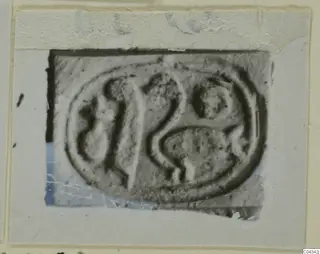 Oval engraved seal or gem with carved curved motifs, shown in a photograph mounted on a card