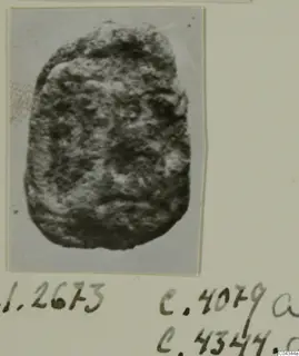 Photograph on a mount of a rounded stone object with a rough, pitted surface, handwritten numbers below