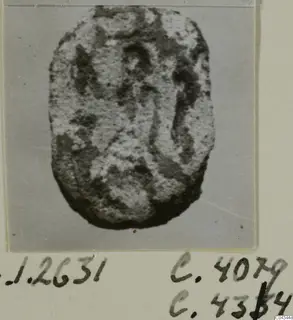 Stone seal or gem with a flat, oval face and worn engraved design, shown on a grey backdrop.