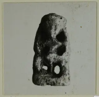 Small upright object with holes, shown on a pale card mount