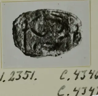 Oval seal or gem with an engraved design, from Ayia Irini, shown on a card with handwritten numbers.