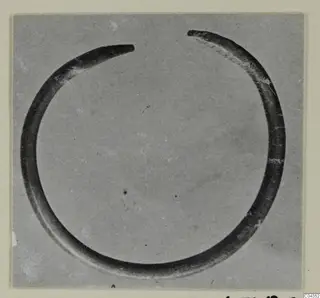 Open silver ring with tapering ends, shown alone against a grey background.