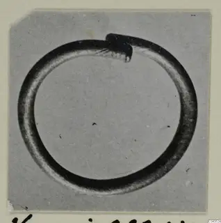 Silver ring from Vouni with one end overlapping the other, photographed on a grey backdrop