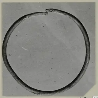 Open silver ring with incised chevron pattern on the band and knobbed ends, photographed on grey card