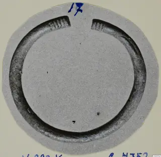 Silver bracelet, an open ring with ribbed ends, shown on a round grey card