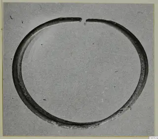 Open silver ring or bracelet with a gap at the top, photographed alone on a grey background