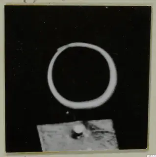 Find photograph of a single plain ring on a black background, with a small grey stand below