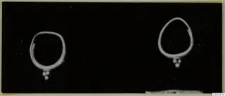 Two gold rings with small bead clusters hanging from them, photographed against black; Lapithos, Kastros tombs.