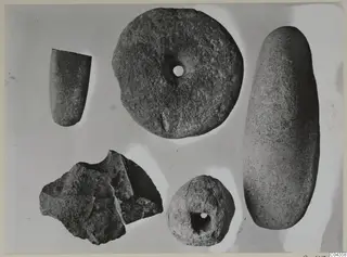 Five stone objects from Petra tou Limniti, including a perforated disc and an elongated oval stone, on a pale background.