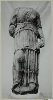 Headless marble statue of a draped standing female figure from Soli, photographed against a plain backdrop.