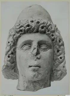 Limestone head of a figure with a tall rounded headdress and curled hair, from Soli