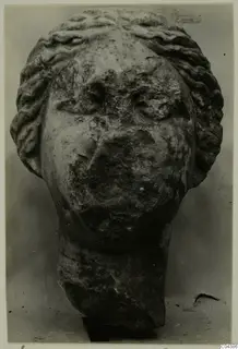 Marble sculpture head from Soli with wavy hair bands and a weathered face