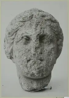 Carved stone head of a man with curly hair and a worn face, from Soli