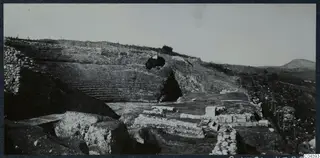 The theatre at Soli, viewed from the east, with tiered seating rising up the slope and excavated stone blocks in the foreground.