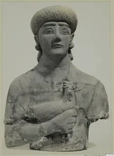 Terracotta Neo-Cypriote bust of a figure in a tall patterned cap, holding a vessel with an animal head against its chest