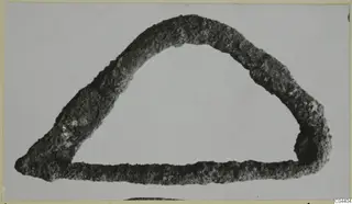 Corroded bronze loop, rounded triangular form, shown alone on a pale background