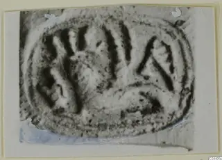Oval glyptic object with incised linear design, shown on a card mount