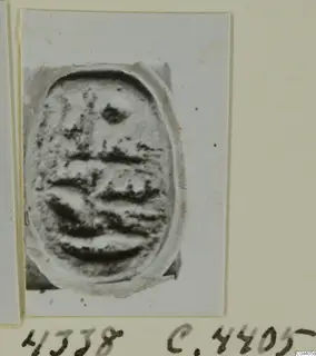 Oval seal or gem from Ayia Irini with dark horizontal grooves on its face, shown on a card mount