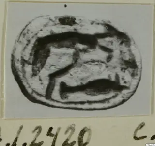 Oval engraved seal stone with a dark incised design, shown on a card mount