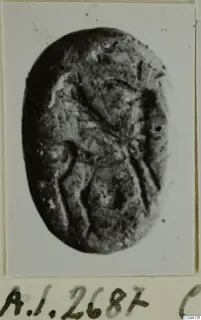 Oval dark stone seal or gem with incised lines, photographed face-on and mounted on a card