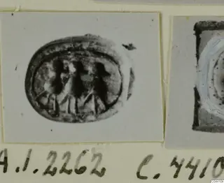 Oval seal with three upright figures engraved on its face, photographed on a card beside a second object