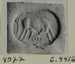 Seal impression from Ayia Irini with an oval design of raised motifs and a dark crescent along one edge