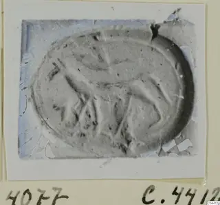 Oval seal or gem with a faint carved design, shown as a photograph mounted on a card.