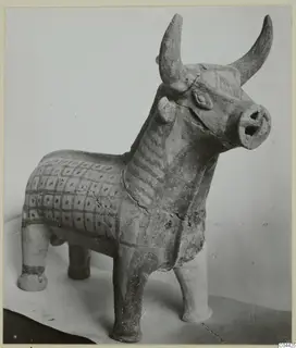 Terracotta figurine of a bull with upturned horns, an open muzzle and a painted grid pattern on its body.