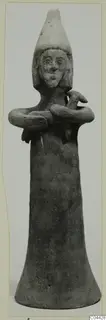 Terracotta figurine of a standing figure with a tall conical headdress and arms folded across the chest.