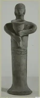 Terracotta figurine of a standing figure holding a cup-shaped vessel at its chest, on a flaring base