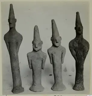 Four terracotta figurines with tall, pointed heads standing side by side